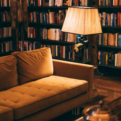 Couch with lamp in study with bookshelf in background